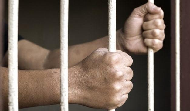 Mãos de homem preso em cela